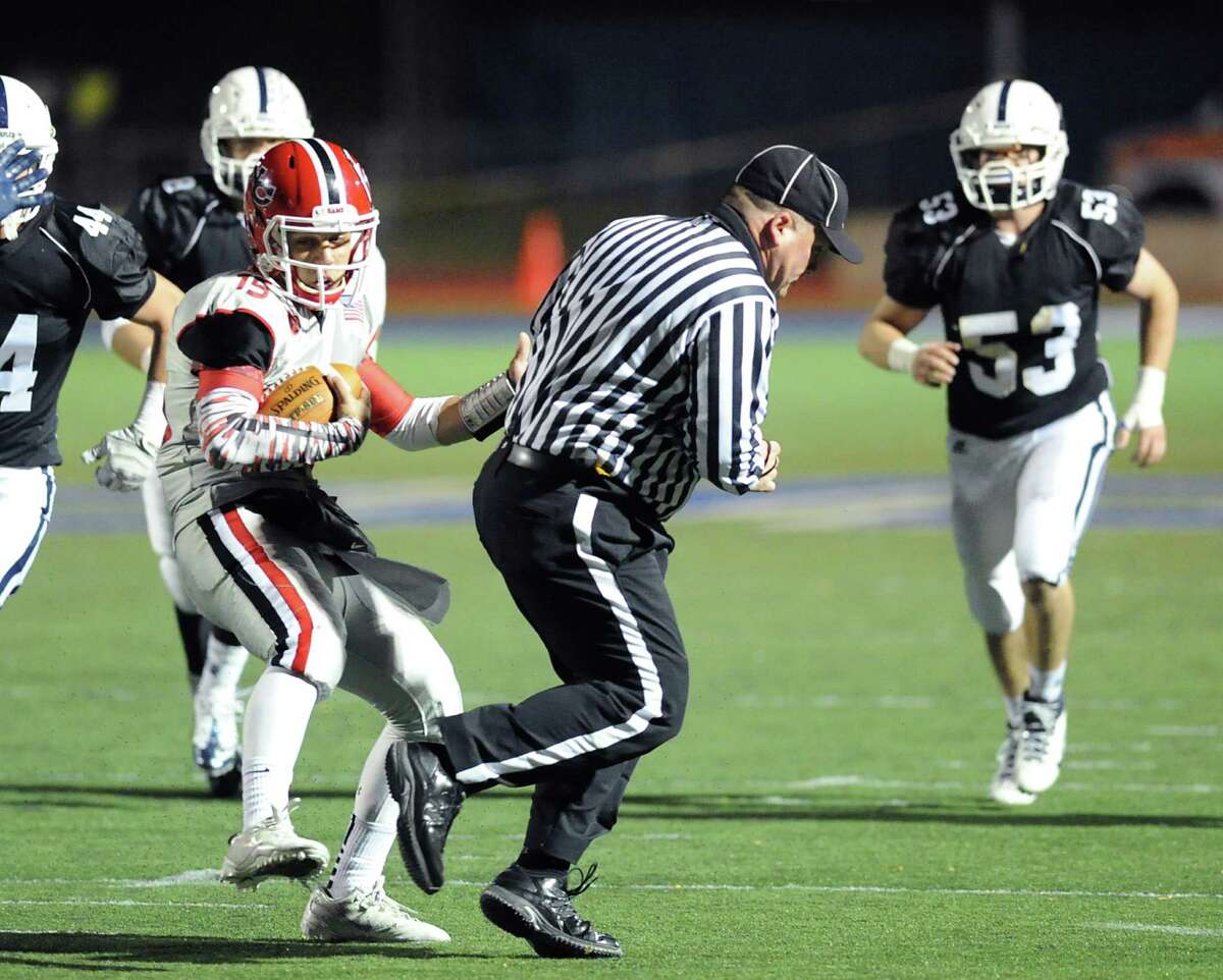 New Canaan quarterback Nick Cascione, at center, runs into a referee during the high School football game between Staples High School and New Canaan High School at Staples in Westport, Friday night, Oct. 25, 2013.