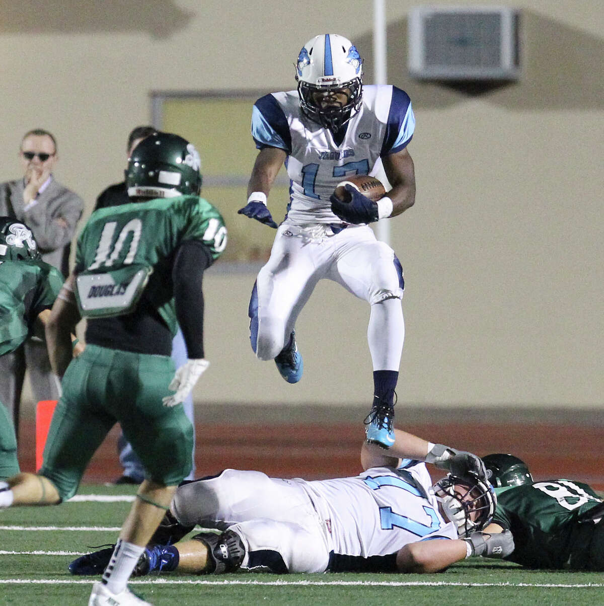 Johnson's Braedon Williams (17) leaps over players during the game against the Reagan Rattlers at Comalander Stadium on Friday, Oct. 25, 2013.