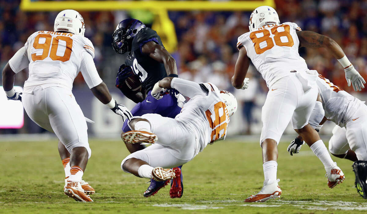 FORT WORTH, TX - OCTOBER 26: Jordan Moore #29 of the TCU Horned Frogs carries the ball against Chris Whaley #96 of the Texas Longhorns, Malcom Brown #90 of the Texas Longhorns, and Cedric Reed #88 of the Texas Longhorns in the first quarter at Amon G. Carter Stadium on October 26, 2013 in Fort Worth, Texas.