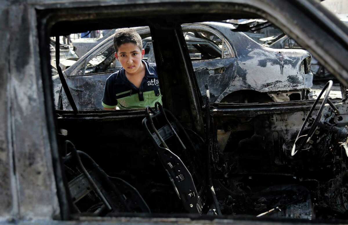 A boy inspects a destroyed car after a bombing in the Shaab neighborhood of Baghdad on Sunday. A wave of attacks, which killed at least 66 people, was the deadliest in the country since Oct. 5.