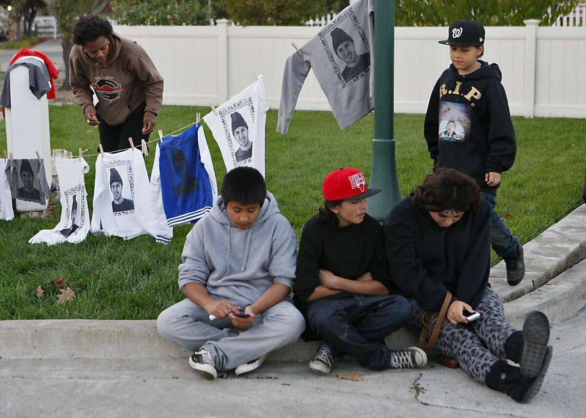 Tonia Coleman hangs screen prints to dry while (left to right) Fernando Alducin, Cristian Sev, Marisol Hernandez and Carlos Sev (above) hangout outside the viewing service for Andy Lopez in Windsor, Calif. on Saturday, Oct. 27, 2013.