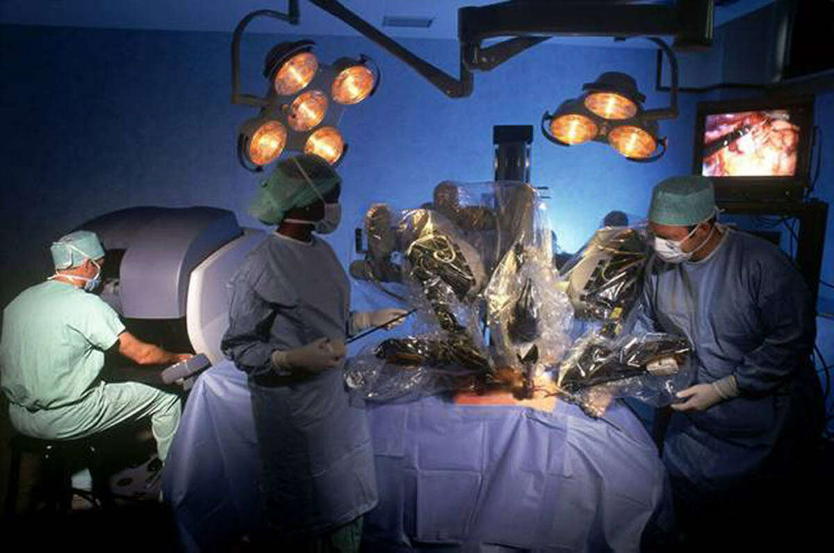 In robot-assisted surgery, the surgeon looks into a high-definition display at a console several feet from the patient. Foot pedals and hand controls maneuver mechanical arms equipped with tools, guided by a 3-D camera that shows the work being done.