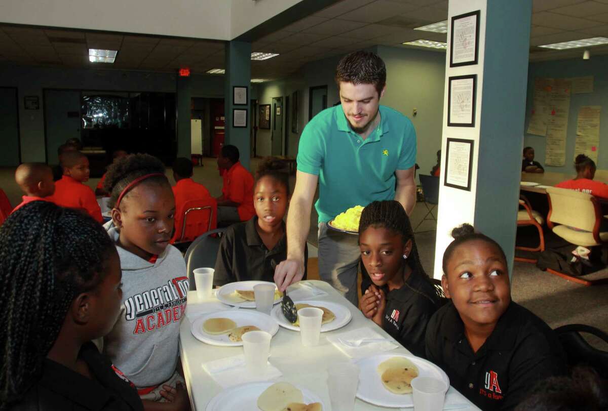 (For the Chronicle/Gary Fountain, September 27, 2013) Josh Eddy of Christian Brothers Automotive, serving breakfast to a group of children at Generation One Academy.