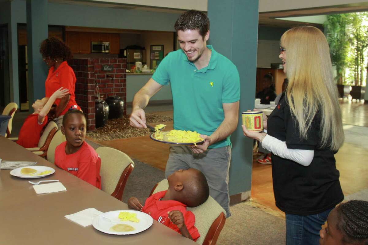 (For the Chronicle/Gary Fountain, September 27, 2013) Josh Eddy of Christian Brothers Automotive, serving breakfast to a group of children at Generation One Academy. On the right is teacher Kelly Morlan.