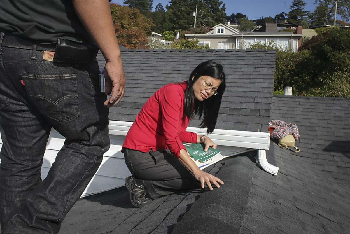 Khoi Senderowicz, (center) a Berkeley rental property owner, and Rudy Diaz, a professional roofer, inspect the new shingling roof installed by Diaz on one of Senderowicz's homes in Berkeley on October 28th 2013.