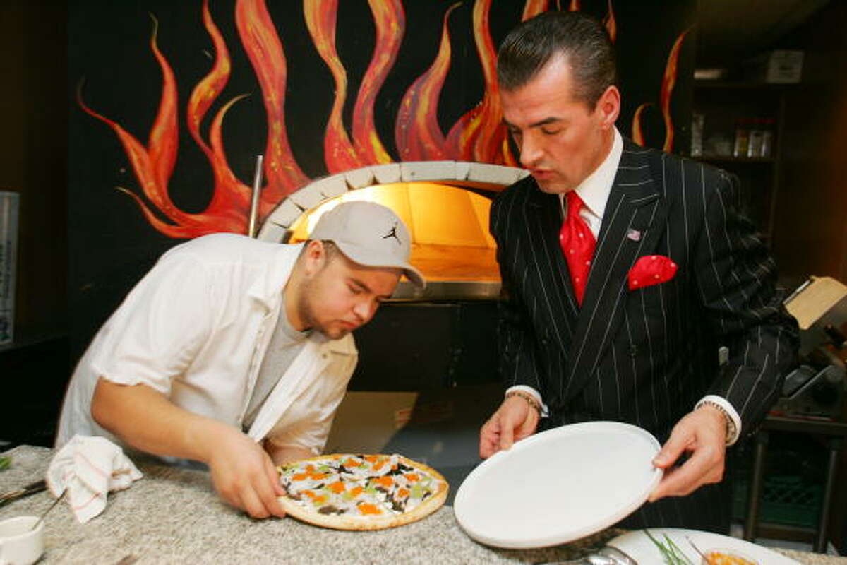 Ulises "Miguel" Virafuentes (left) gingerly helps plate a $1,000 luxury pizza pie with Nino's Bellissima Pizza restaurant owner Nino Selimaj. The pricey pizza is topped with sliced lobster tail, creme fraiche and four different kinds of caviar.
