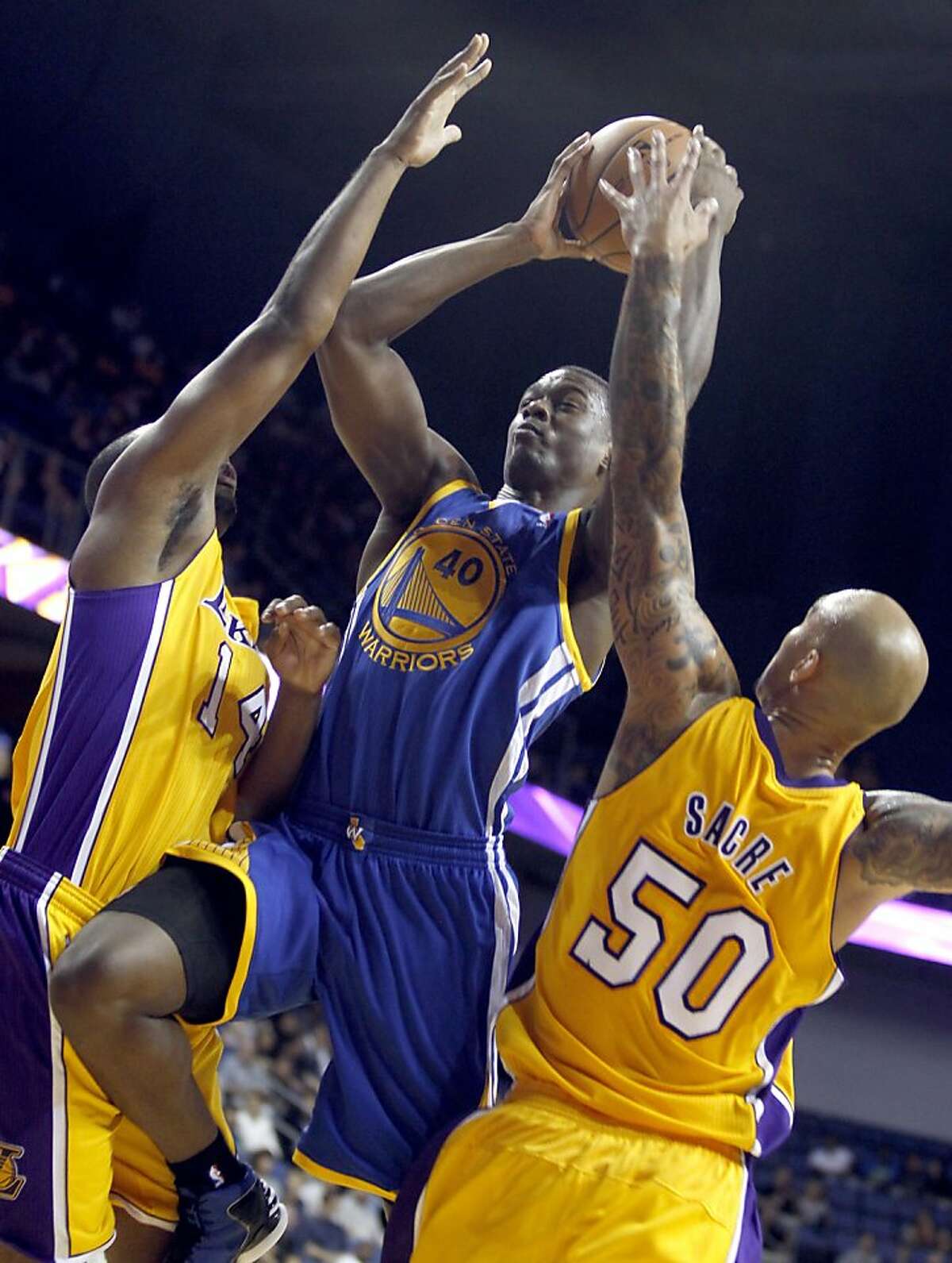 Golden State Warriors forward Harrison Barnes, center, splits the defense of Los Angeles Lakers forward Marcus Landry, left, and Lakers center Robert Sacre (50) in the fourth quarter during an NBA basketball preseason game Saturday, Oct. 5, 2013, in Ontario, Calif. Lakers won the game 104-95. (AP Photo/Alex Gallardo)