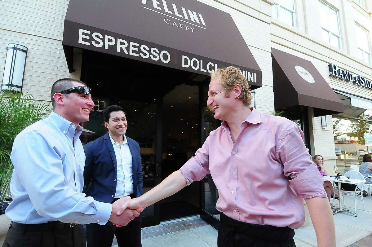 Massimiliano Massolini (cq) and Jacob Lopez (cq) are greeted by Paolo Fronza (cq) in front of his Fellini Caffee shop Wednesday 10/23/13. Photo by Tony Bullard.