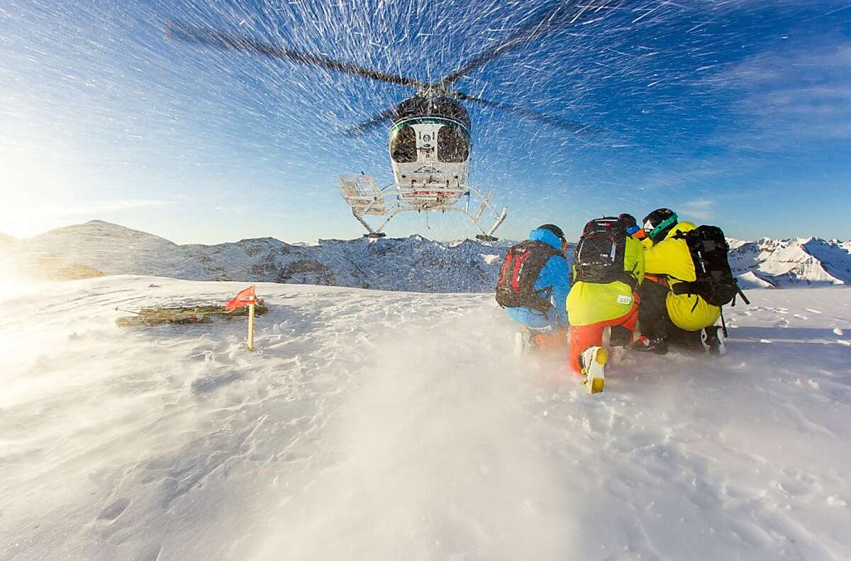 Skiers take shelter as a helicopter leaves them to explore some runs in the San Juan mountains outside Telluride.