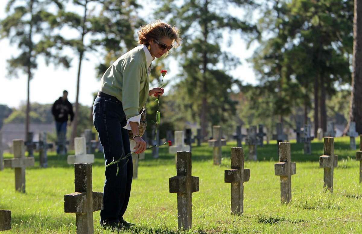Restorative Justice Ministries Networks' Amy Lea Iles places a flower against a headstone at Capt. Joe Byrd Cemetery, also known as "Peckerwood Hill," for All Souls' Day on Saturday in Huntsville.