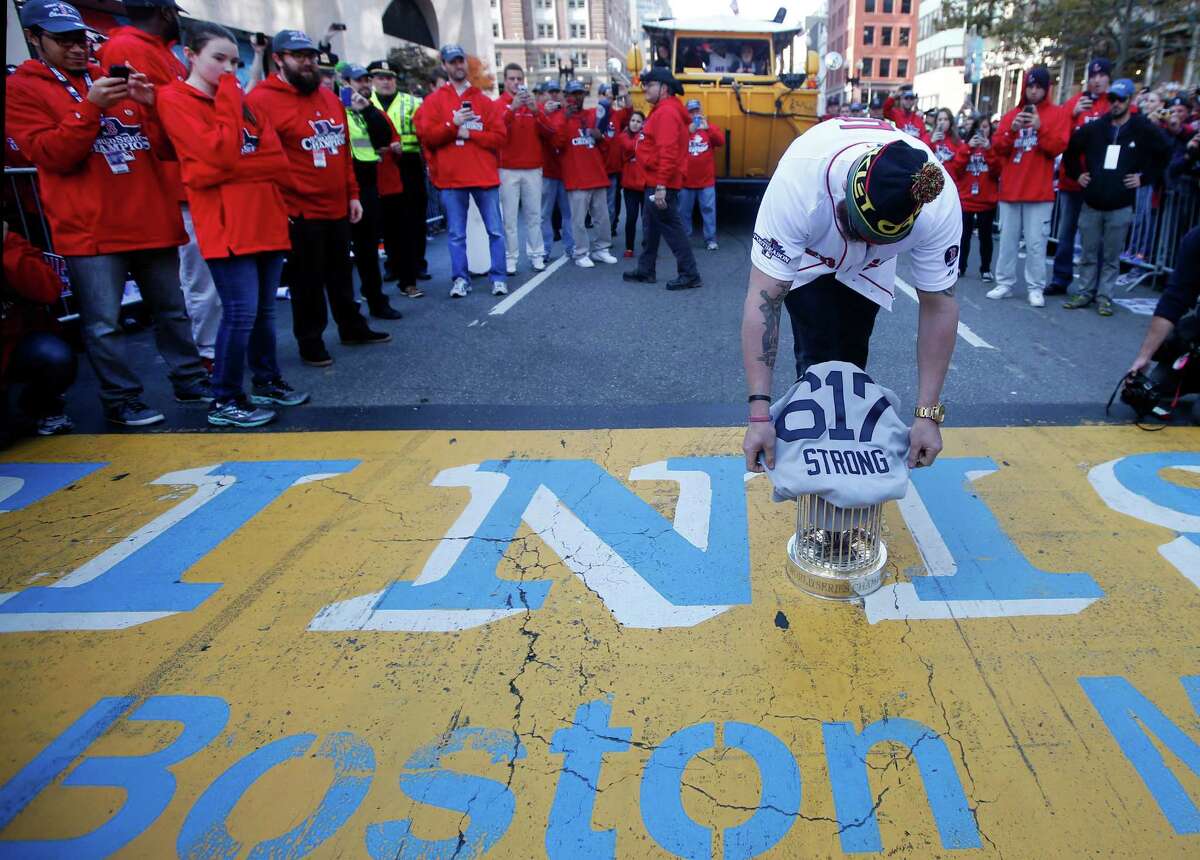 Outfielder Jonny Gomes places the World Series championship trophy and a Red Sox jersey at the Boston Marathon finish line on Saturday to honor those affected by the Boston Marathon bombing.