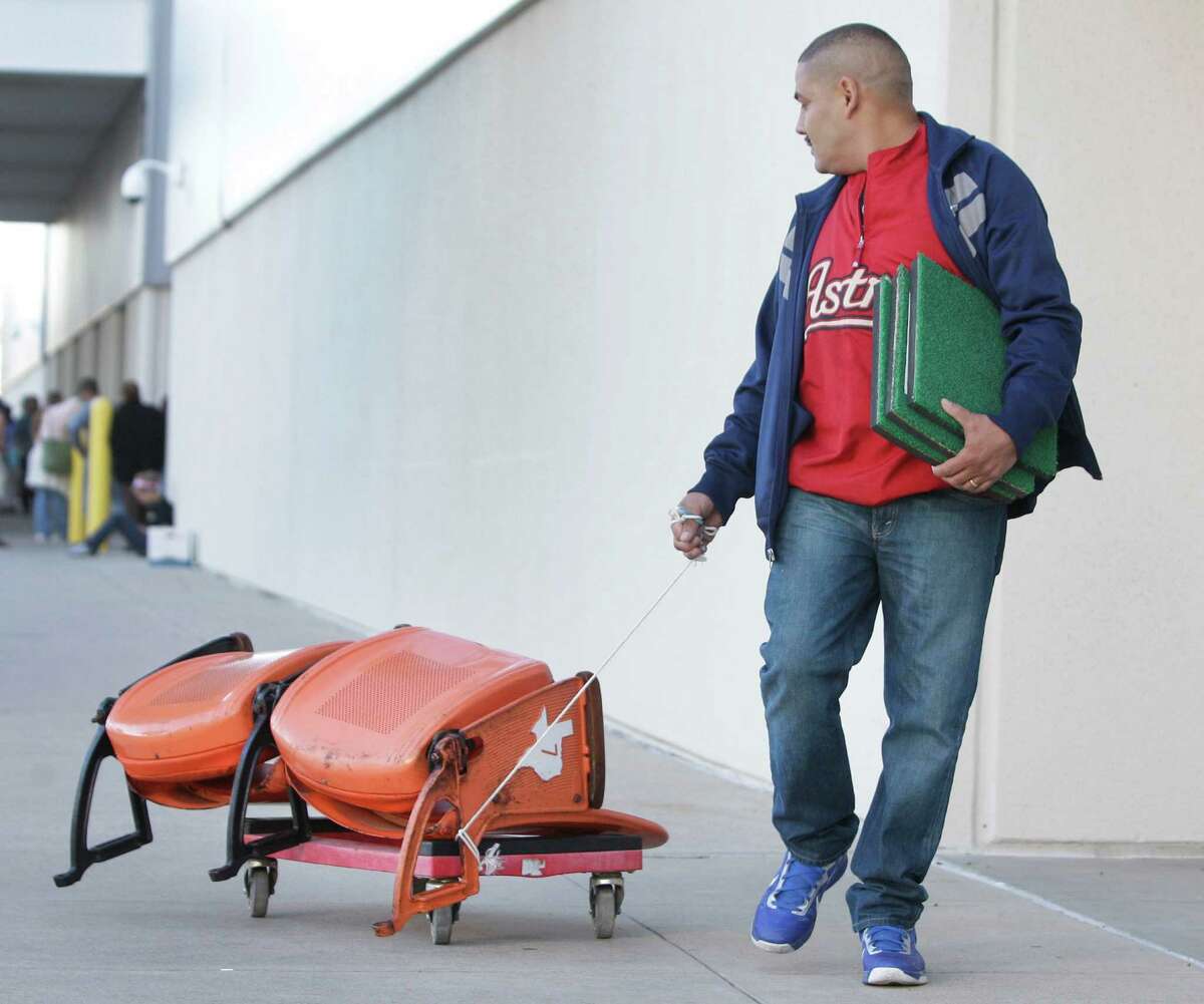 Ramon Lopez pulls a pair of seats and carries Astrodome turf he purchased during the sale at Reliant Center of Astrodome items Saturday, Nov. 2, 2013, in Houston.