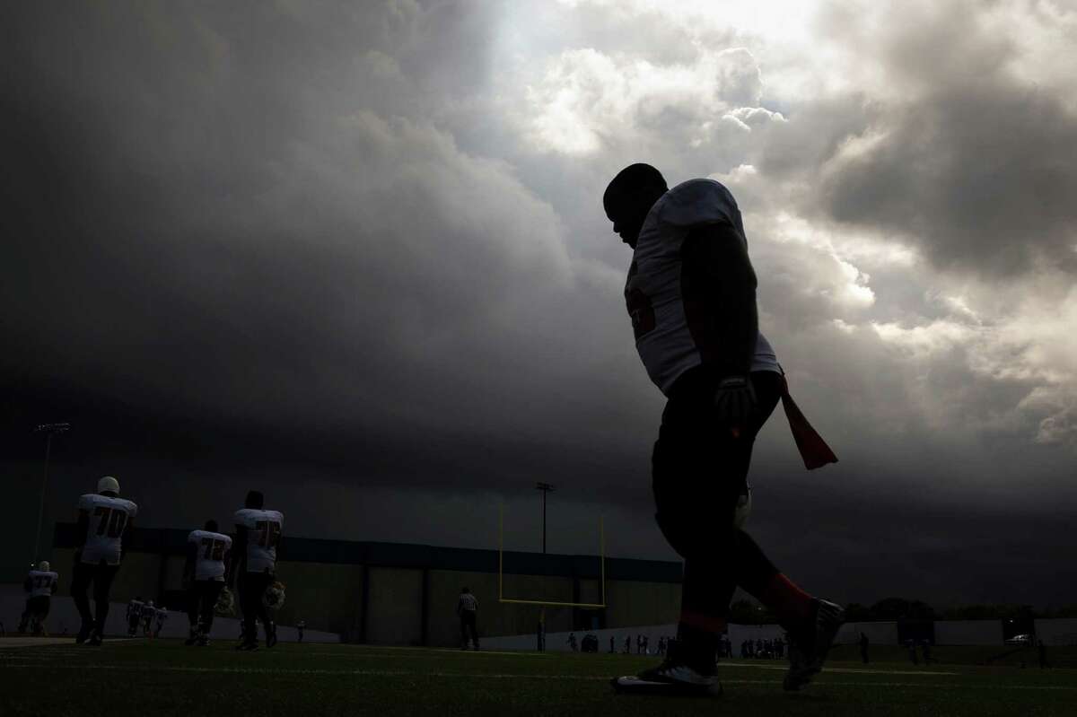 As dark storm clouds roll over the stadium Scarborough lineman Kelderick Suazo heads for the locker room at halftime of a football game against Sterling at Barnett Stadium.  ( Smiley N. Pool / Houston Chronicle )
