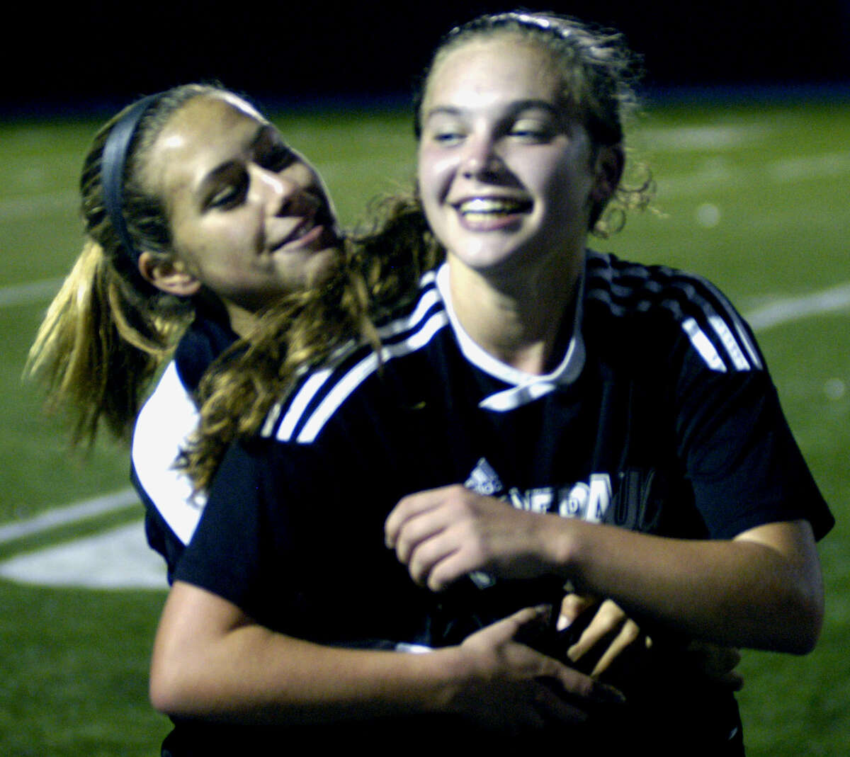 Panther sophomore Caly Farina, right, gets a conmgratulatory hug from a teammate after scoring the game-winning goal for Pomperaug in a 2-1 double-overtime victory over New Milford in the South-West Conference girls' soccer final at Newtown High. Nov. 1, 2013