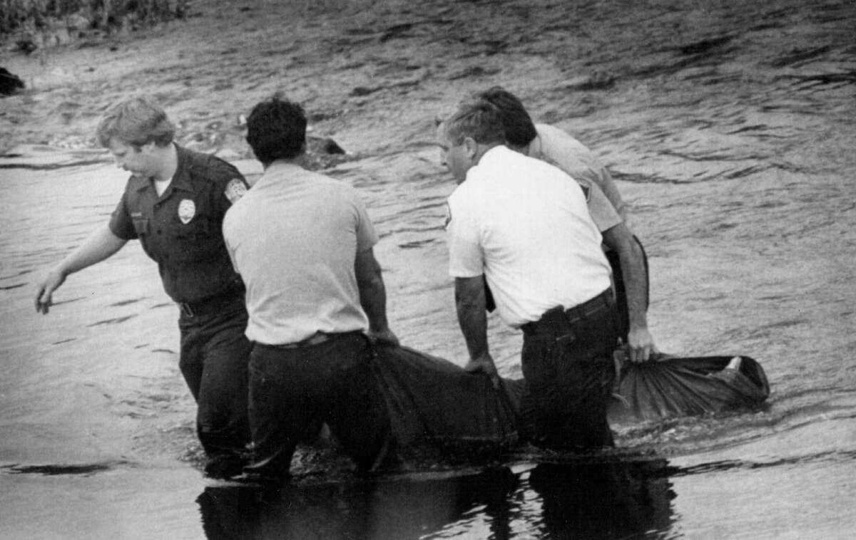 Officials remove the body of 16-year-old Wendy Lee Coffield from the Green River on July 15, 1982. The discovery of the body behind a meat packing plant was the first clue police had to the developing nightmare of the Green River serieal killer's actions. Photo filed July 15, 1982. (Copyright MOHAI, Seattle Post-Intelligencer Collection, 2000.107)