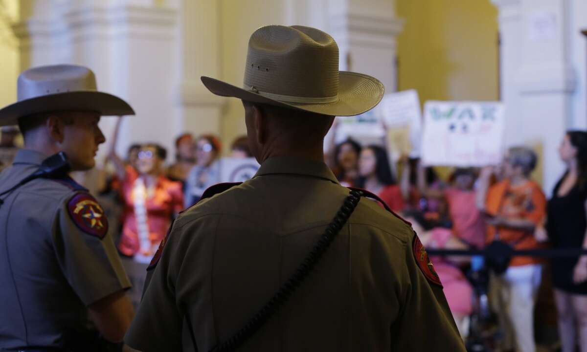 Texas state troopers stand in the Capitol rotunda as they watch opponents of HB 2, an abortion bill, after the Texas House made their final vote, Wednesday, July 10, 2013, in Austin, Texas. The approved bill, which now goes to the Texas Senate, would require doctors to have admitting privileges at nearby hospitals, only allow abortions in surgical centers, dictate when abortion pills are taken and ban abortions after 20 weeks. (AP Photo/Eric Gay)