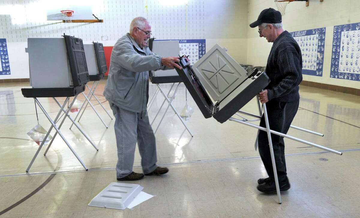 Joe Cowell, left, Republican assistant registrar, and Denis Bouffard, polling place moderator, set up the gym at Stadley Rough Elementary School for Tuesday's elections, Monday, Nov. 4, 2013.
