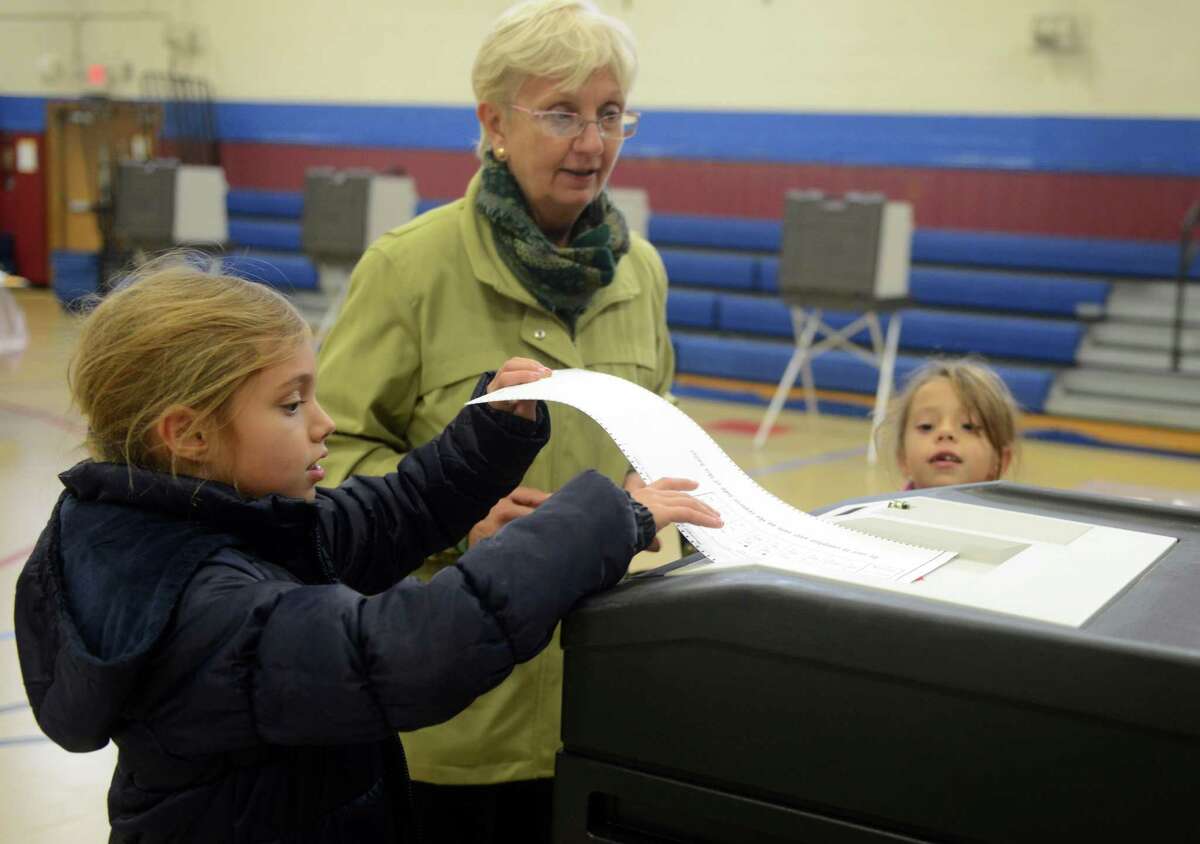 Cornelia Tarnoski gets some help casting her vote from granddaughters Anais Salageanu, 8, left, and Adriana Salageanu, 6, at Irving School in Derby, Conn. Tuesday, Nov. 5, 2013.