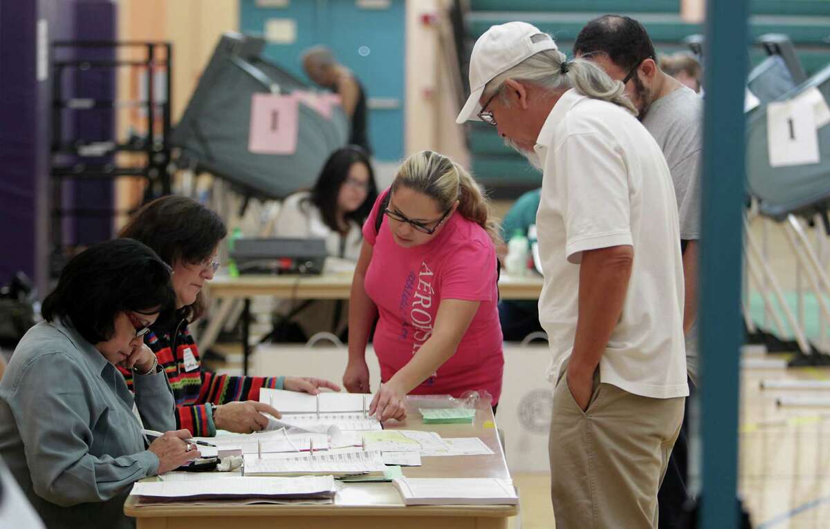 Poll workers sign in voters at the Denver Harbor Park Community Center on Tuesday. A new state law requires residents to produce photo identification before casting their ballots on Election Day.