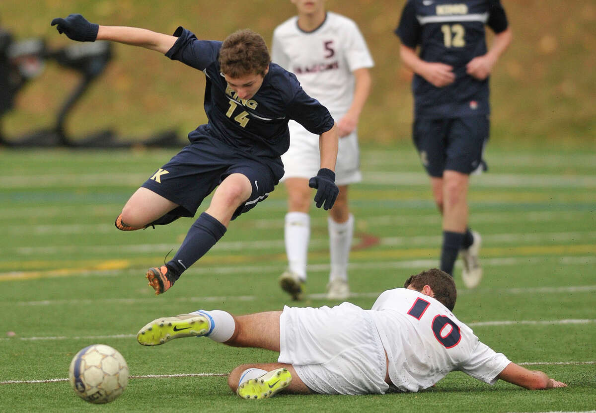 King's Jack Lineberry jumps over the sliding Brendan Bieder, of Greens Farms Academy, during their FAA semifinal game at King school in Stamford, Conn., on Wednesday, Nov. 6, 2013. Greens Farms Academy won, 1-0.
