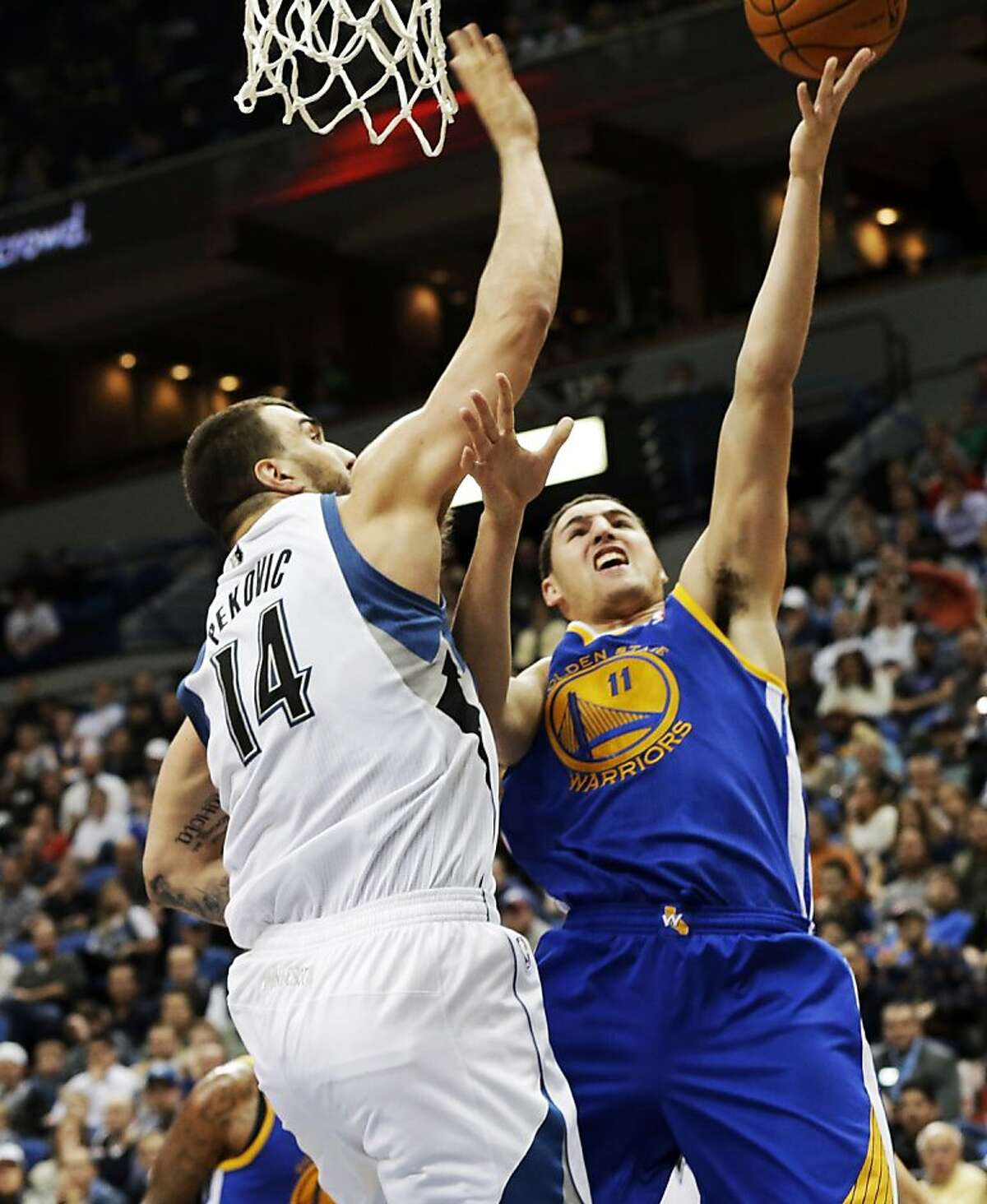 Golden State Warriors' Klay Thompson, right, shoots as Minnesota Timberwolves' Nikola Pekovic, of Montenegro, defends in the second half of an NBA basketball game Wednesday, Nov. 6, 2013, in Minneapolis. Thompson led the Warriors with 30 points in their 106-93 win. (AP Photo/Jim Mone)