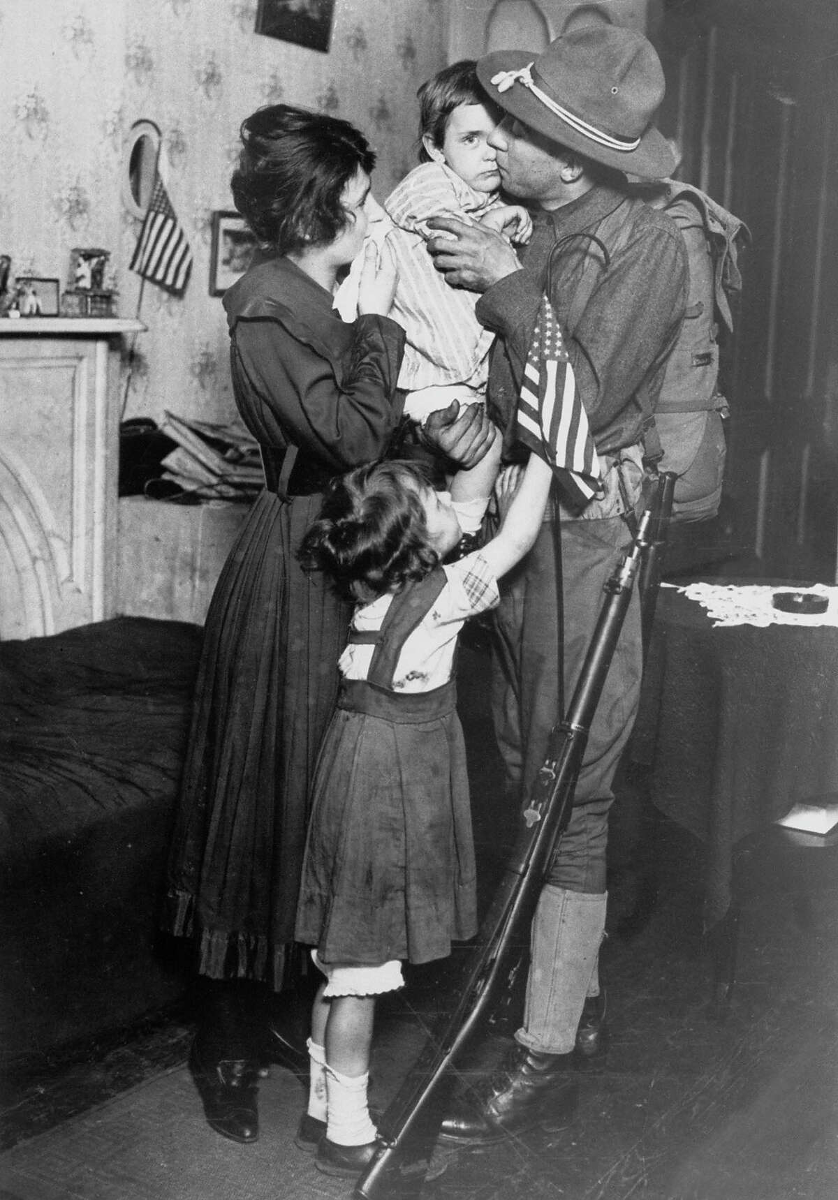 NY National Guardsman Private T. P. Loughlin of 69th New York National Guard Regiment, kissing his little child goodbye as he bids farewell to family before reporting to training camp during WWI, 1917.