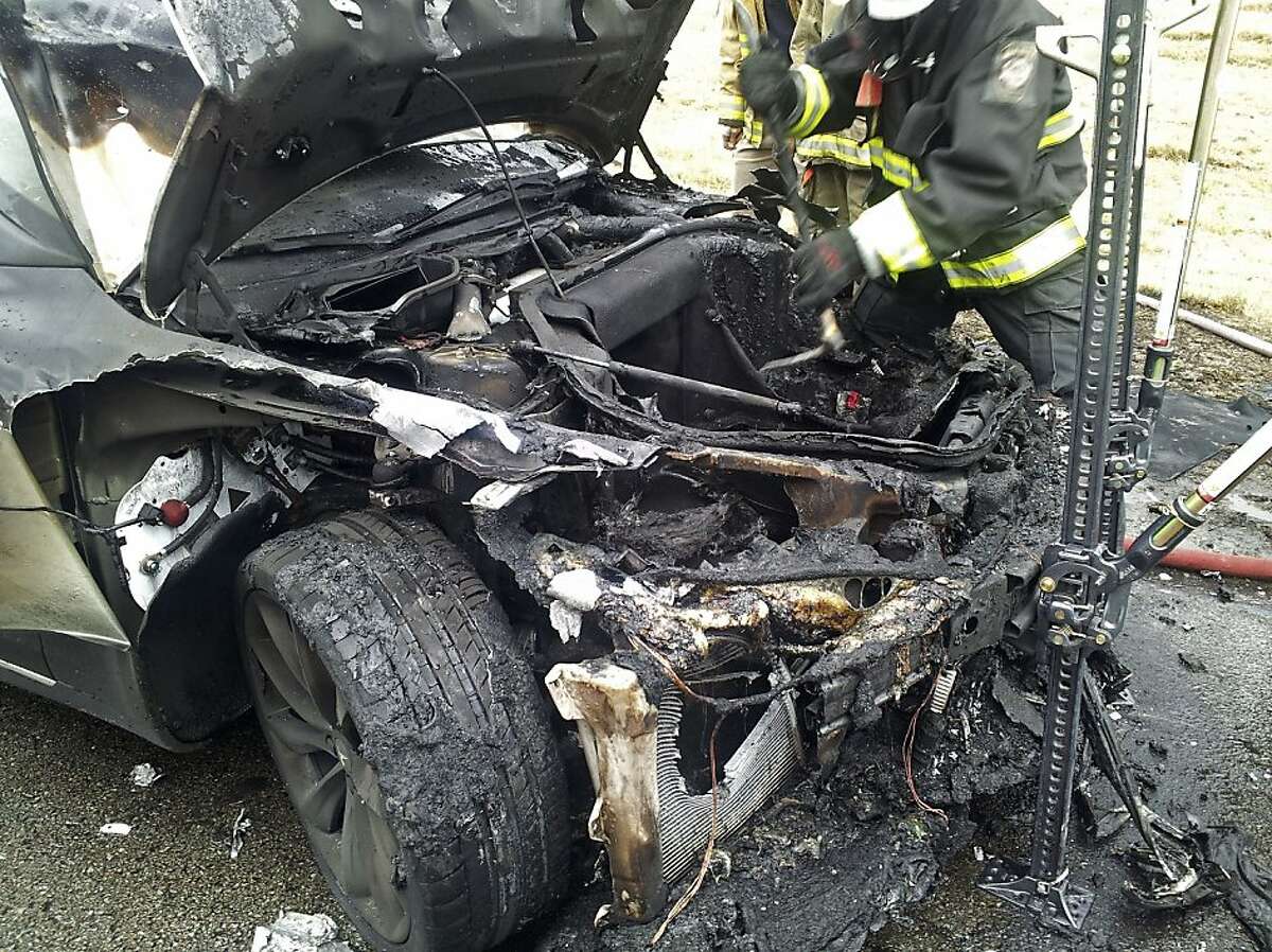 In this Wednesday, Nov. 6, 2013 photo provided by the Tennessee Highway Patrol, emergency workers respond to a fire on a Tesla Model S electric car in Smyrna, Tenn. Spokeswoman Liz Jarvis Shean says Tesla has sent a team to Tennessee to investigate the fire. Two other Model S cars have caught fire in the past five weeks, one near Seattle and the other in Mexico. (AP Photo/Tennessee Highway Patrol)