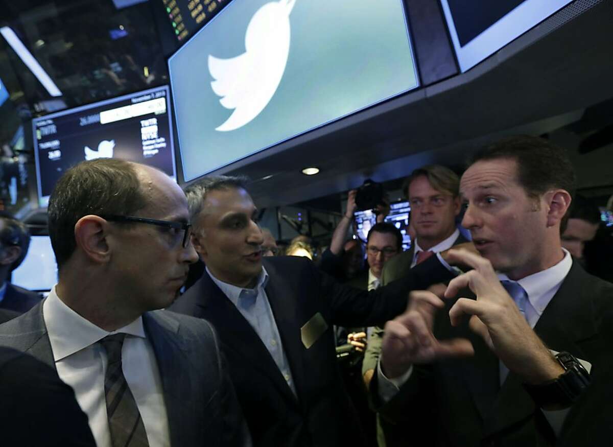Twitter CEO Dick Costolo, left, and Mike Gupta, center, chief financial officer of Twitter, talk with specialist Glenn Carell during Twitter's IPO, on the floor of the New York Stock Exchange, Thursday, Nov. 7, 2013. If Twitter's bankers and executives were hoping for a surge on the day of the stock's public debut, they got it. The stock opened at $45.10 a share on its first day of trading, 73 percent above its initial offering price. (AP Photo/Richard Drew)