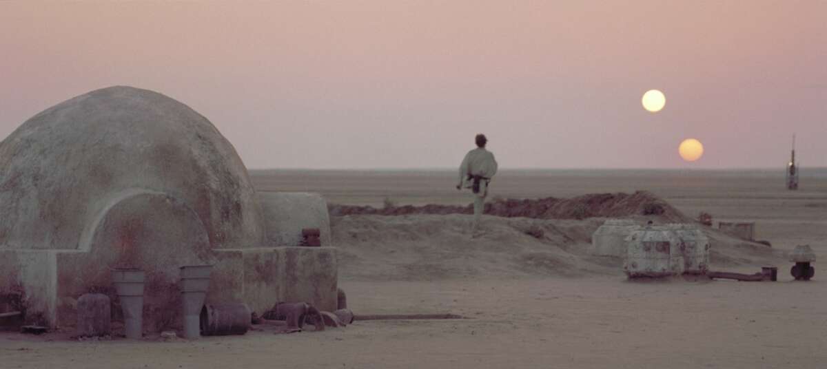 After discussing his future plans with his Uncle Owen, Luke Skywalker leaves the Lars Homestead and heads towards the vista to watch the twin suns of Tatooine set while he reflects upon his destiny in a scene from the film "Star Wars.".