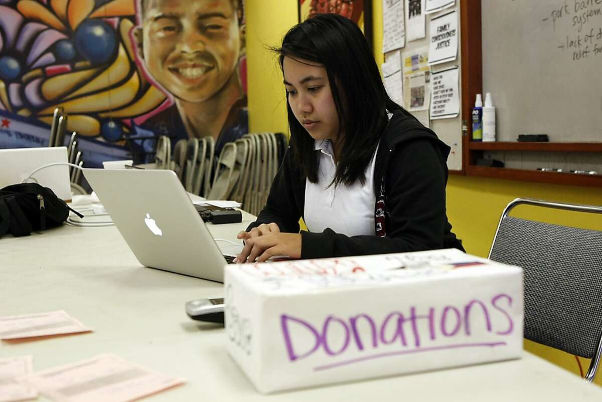 Staff member Aurora Victoria David works on her phone as a box for donations to help victims of Typhoon Haiyan in the Philippines sits next to her at the Filipino Community Center in San Francisco, CA Friday, November 8, 2013.