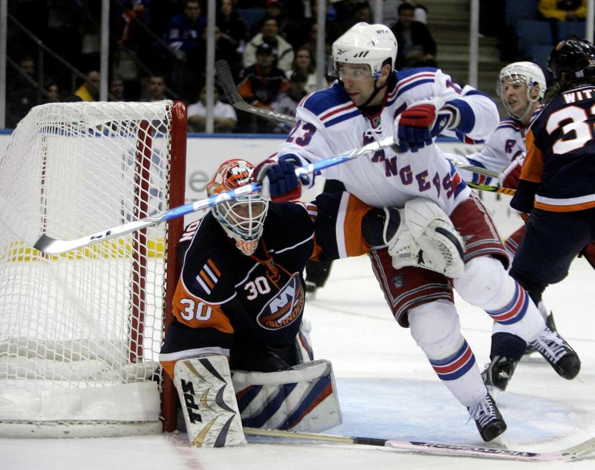 New York Islanders goalie Dwayne Roloson, left, keeps an arm on New York Rangers' Chris Drury during the third period of the NHL hockey game Wednesday, Oct. 28, 2009, in Uniondale, N.Y. The Islanders beat the Rangers, 3-1. (AP Photo/Seth Wenig)