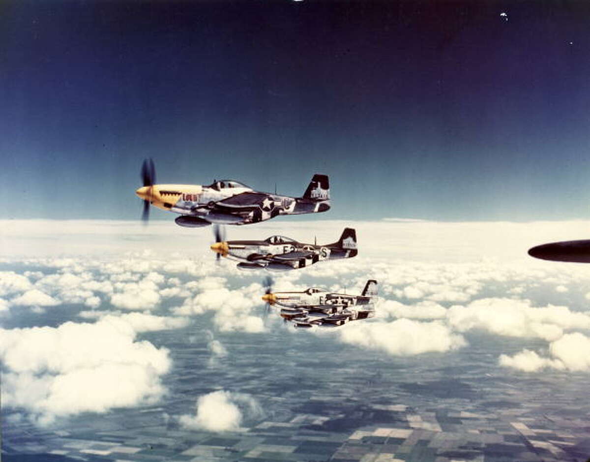 Aerial view of a squadron of North American Aviation P-51 Mustang fighter planes (including one nickanemd 'Lou IV') in flight over England, 1940s.