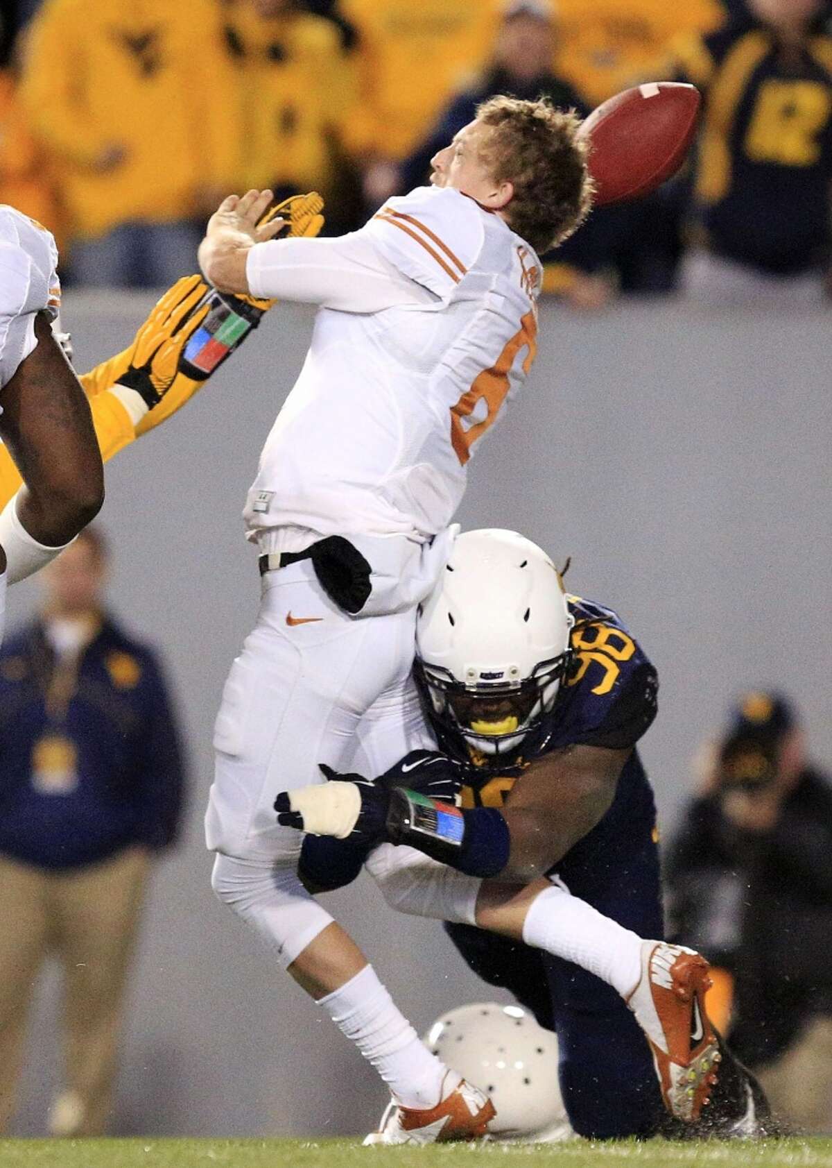 Texas quarterback Case McCoy (6) is sacked by West Virginia's Will Clarke (98) during the second quarter of an NCAA college football game in Morgantown, W.Va., on Saturday, Nov. 9, 2013. (AP Photo/Christopher Jackson)