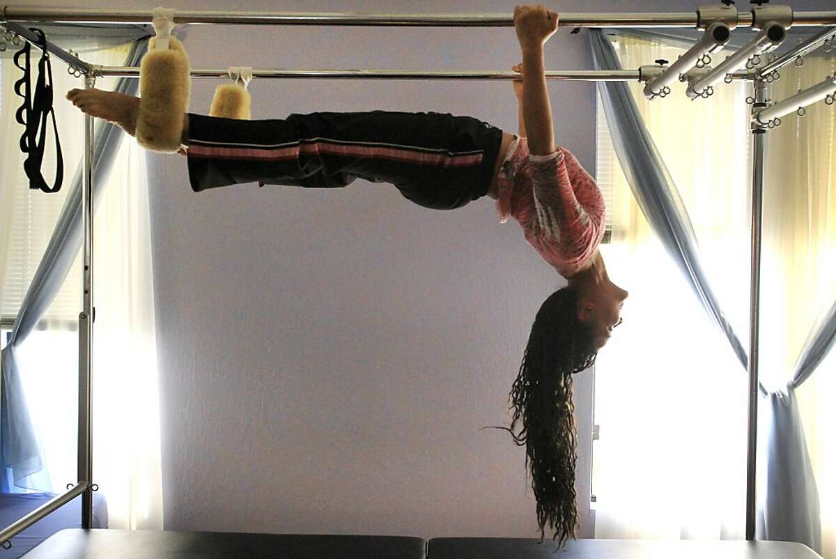 Tonya Marie Amos demonstrates what she calls the "bat girl" move on the trapeze table November 7, 2013 at Aspire Pilates Center in Concord, Calif.