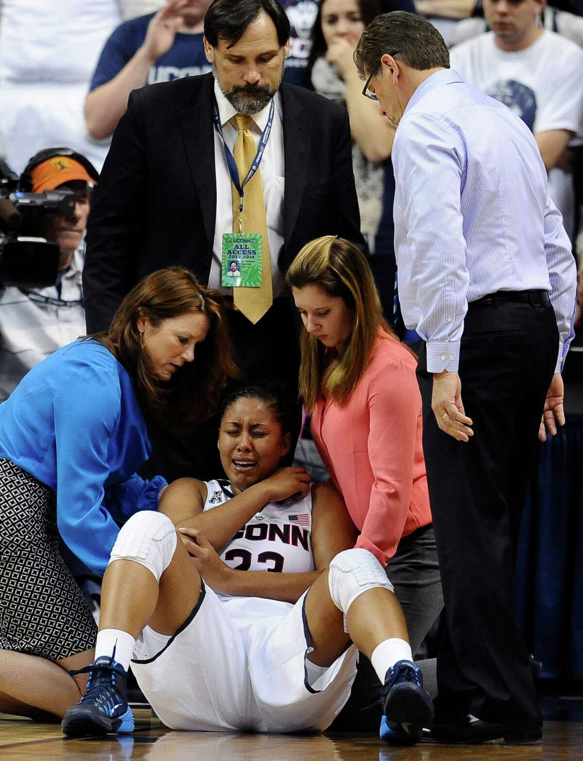 Connecticut head coach Geno Auriemma, right, looks at injured player Kaleena Mosqueda-Lewis, center, as she is tended to by assistant athletic trainer Rosemary Ragle, left, Team Physician Dr. Thomas Trojian, top center, and student athletic trainer Lauren Sheldon, second from right, during the second half of an NCAA college basketball game, Monday, Nov. 11, 2013, in Storrs, Conn. Mosqueda-Lewis left the game with an injury to her right elbow. Connecticut won 76-57.