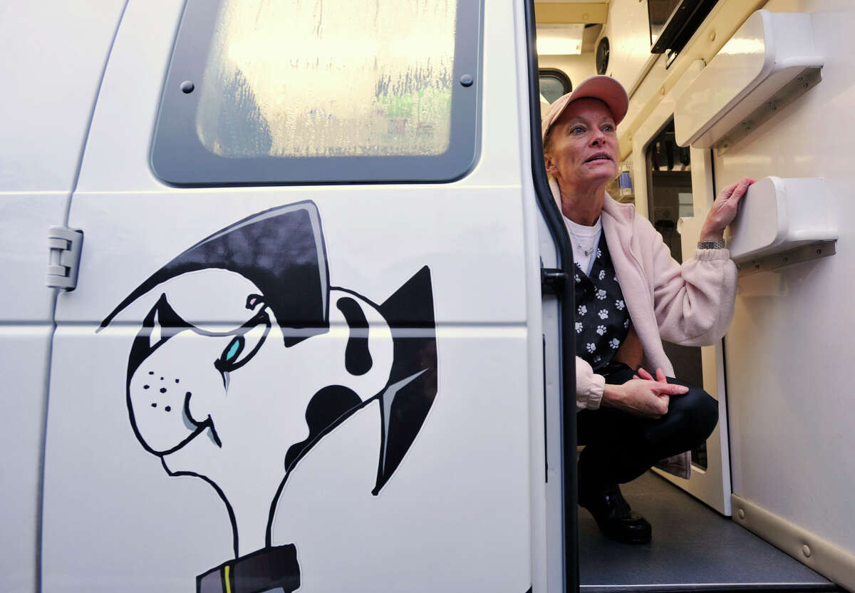 Janine McCormick, owner of Wash and Groom Spa, a mobile dog grooming service, crouches inside her van outside her home in Stamford, Conn., on Tuesday, Nov. 12, 2013.