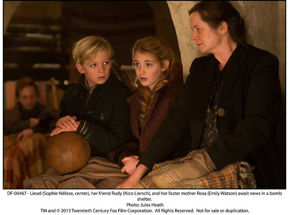 Liesel (Sophie NŽlisse, center), her friend Rudy (Nico Liersch), and her foster mother Rosa (Emily Watson) await news in a bomb shelter.