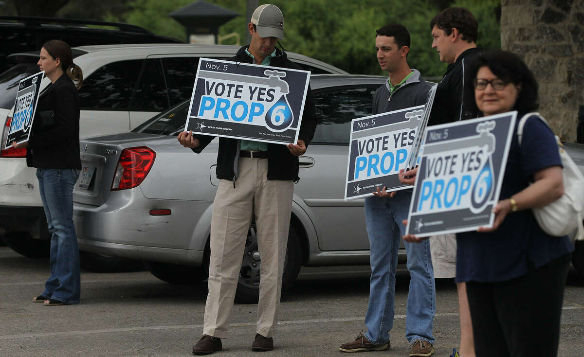 Supporters of Proposition 6 hold signs during early voting. Now that the amendment to fund water projects has passed, Texans should get involved in the regional water planning process.
