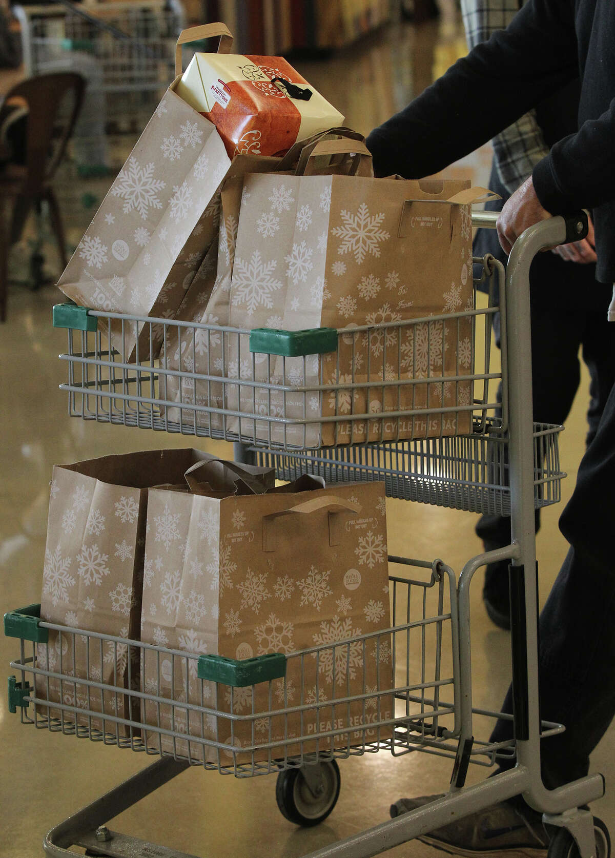 A customer pushes paper bags full of groceries on a cart Thursday November 14, 2013. Many retailers use single-use plastic bags but Whole Foods has phased them out and uses paper and reusable bags. They also give discounts to customers that reuse their paper bags and reusable bags.