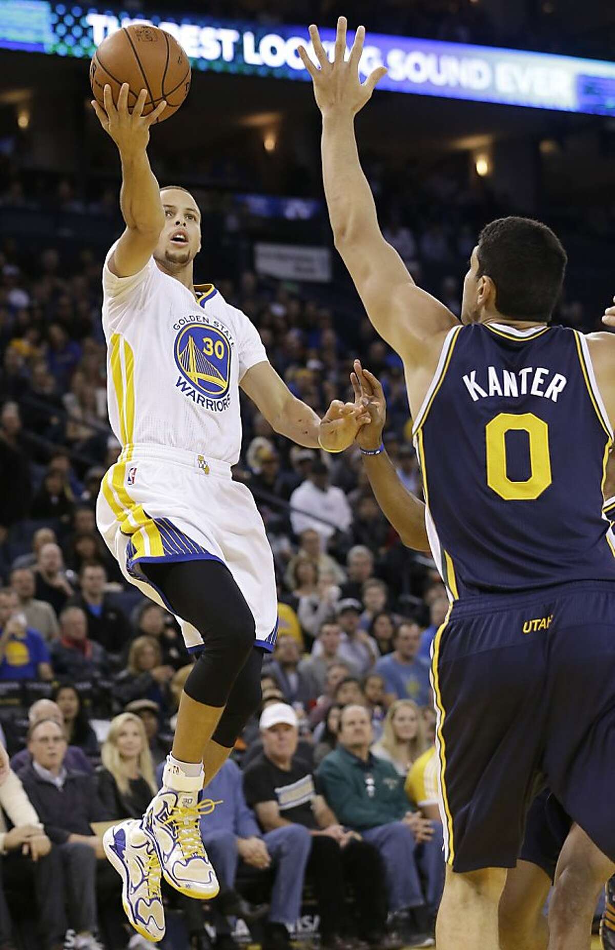 Golden State Warriors shooting guard Stephen Curry (30) shoots against Utah Jazz center Enes Kanter (0) during the first quarter of an NBA basketball game in Oakland, Calif., Saturday, Nov. 16, 2013. (AP Photo/Jeff Chiu)