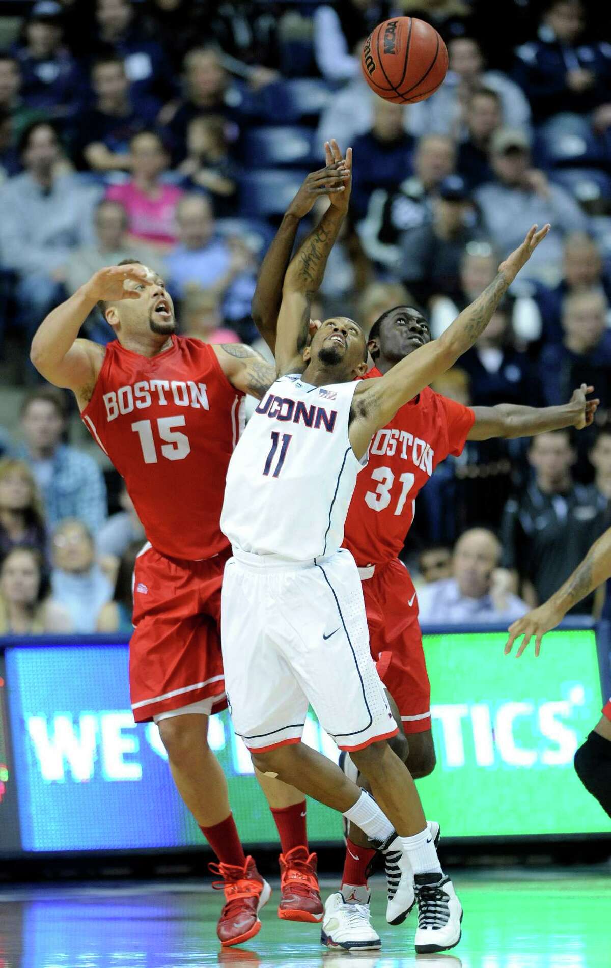 Boston University's Dom Morris (15) and Malik Thomas (31) fight for a rebound with Connecticut's Ryan Boatright (11) during the first half of an NCAA college basketball game in Storrs, Conn., on Sunday, Nov. 17, 2013.