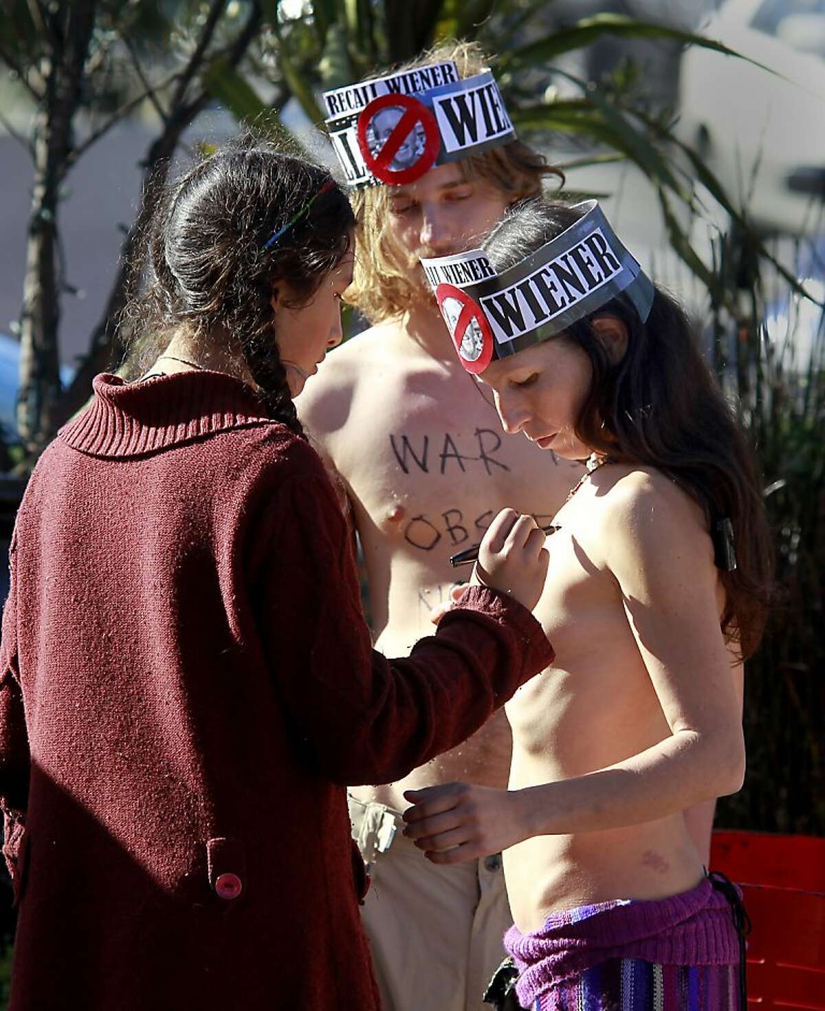 Inti Gonzalez (left) wrote a message of support on her mother's body, Gypsy Taub, before the start of the rally Sunday November 17, 2013 in San Francisco, Calif. Police arrested and cited a group of nudists who staged a rally at the corner of Market and Castro Streets, violating the city's nudity ban.
