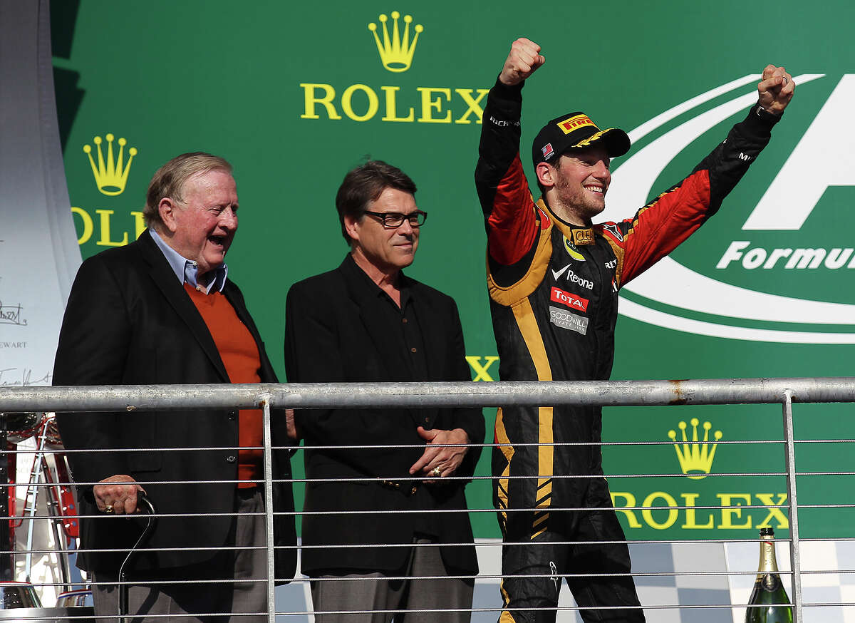 COTA co-owner B.J. "Red" McCombs (from left) and Texas Governor Rick Perry watch Lotus F1 driver and USGP second place winner Romain Grosjean react to the crowd after the Formula One United States Grand Prix at the Circuit of the Americas near Austin, Texas on Sunday, Nov. 17, 2013. Current World Champion Sebastian Vettle finished first followed by Grojean and in third was Vettel's teammate, Mark Webber.