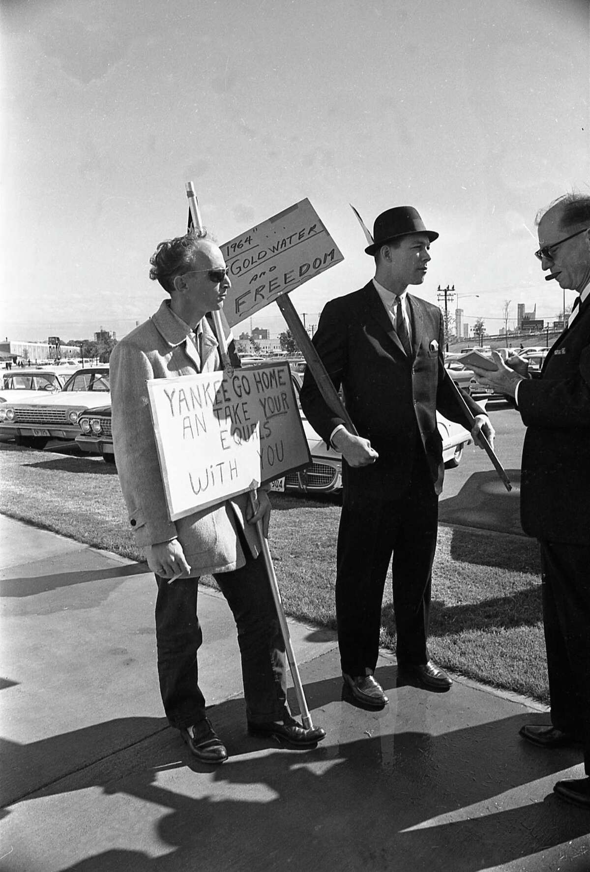 Dallas protesters with anti-Kennedy placards await the arrival of President John F. Kennedy.