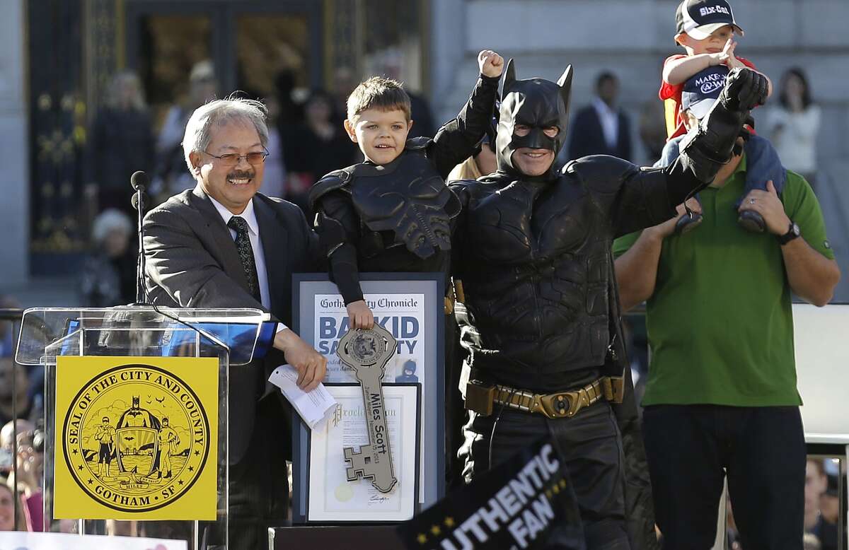 Miles Scott, dressed as Batkid, second from left, raises his arm next to Batman at a rally outside of City Hall with Mayor Ed Lee, left, and his father Nick and brother Clayton, at right, in San Francisco, Friday, Nov. 15, 2013. Scott was called into service on Friday morning by San Francisco Police Chief Greg Suhr to help fight crime, as San Francisco turned into Gotham City as city officials helped fulfill the 5-year-old leukemia patient's wish to be "Batkid," The Greater Bay Area Make-A-Wish Foundation says. He was diagnosed with leukemia when he was 18 months old, finished treatment in June and is now in remission, KGO-TV reported. (AP Photo/Jeff Chiu)