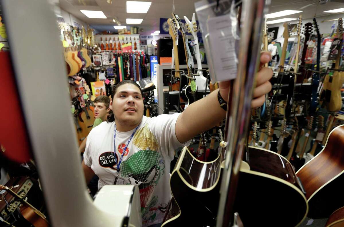 In this Tuesday, Sept. 24, 2013 photo Kevin Sandoval, of Chelsea, Mass., places a guitar on a rack after trying the instrument out at a music store, in Lowell, Mass. The government reports how much U.S. businesses adjusted their stockpiles in September on Wednesday, Nov. 20, 2013. (AP Photo/Steven Senne) ORG XMIT: NYBZ122