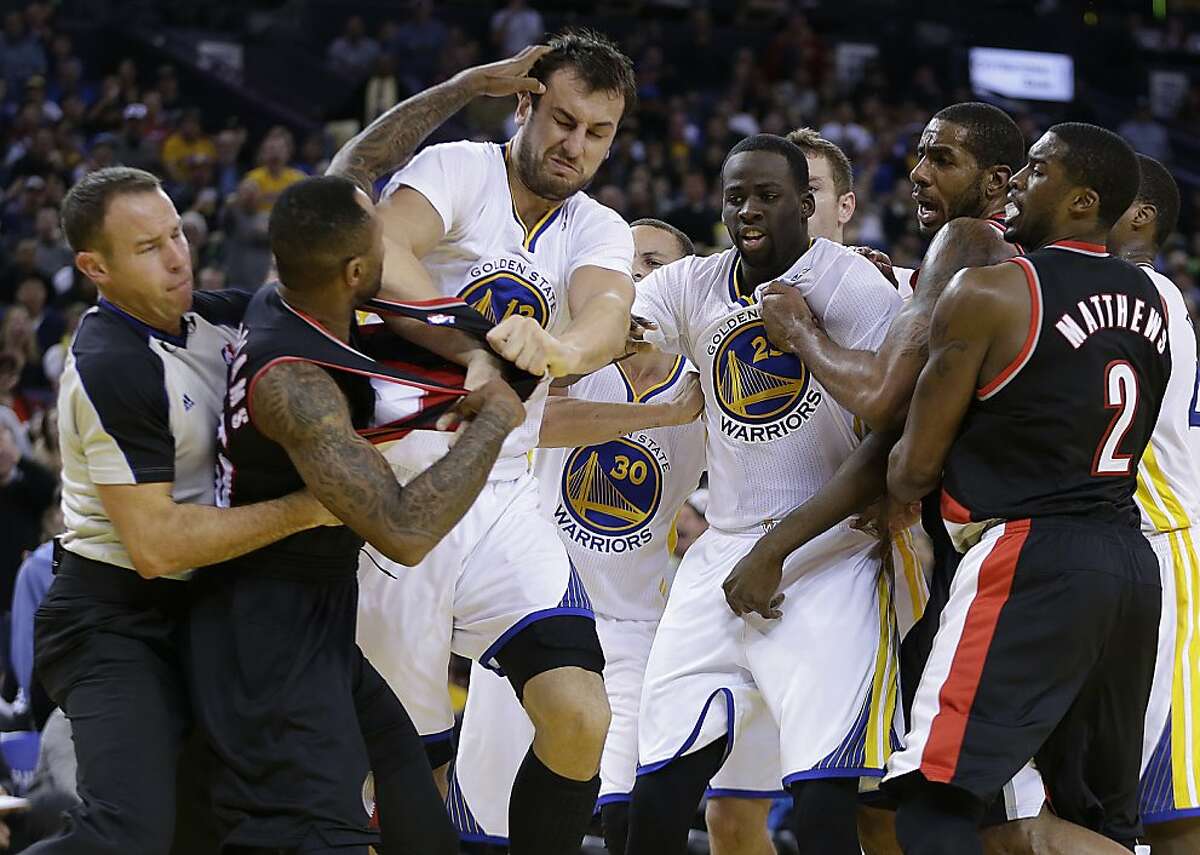 Portland Trail Blazers' Mo Williams, left, is restrained by a referee, left, as he fights with Golden State Warriors' Andrew Bogut (12) during the second half of an NBA basketball game Saturday, Nov. 23, 2013, in Oakland, Calif. Trail Blazers Wesley Matthews, Mo Williams, and Warriors' Draymond Green were ejected from the game. (AP Photo/Ben Margot)