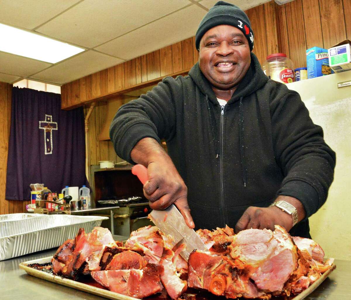 Pastor Willie Bacote carves up hams and pork roast butts in preparation for Thanksgiving Tuesday Nov. 19, 2013, in Troy, NY. (John Carl D'Annibale / Times Union)