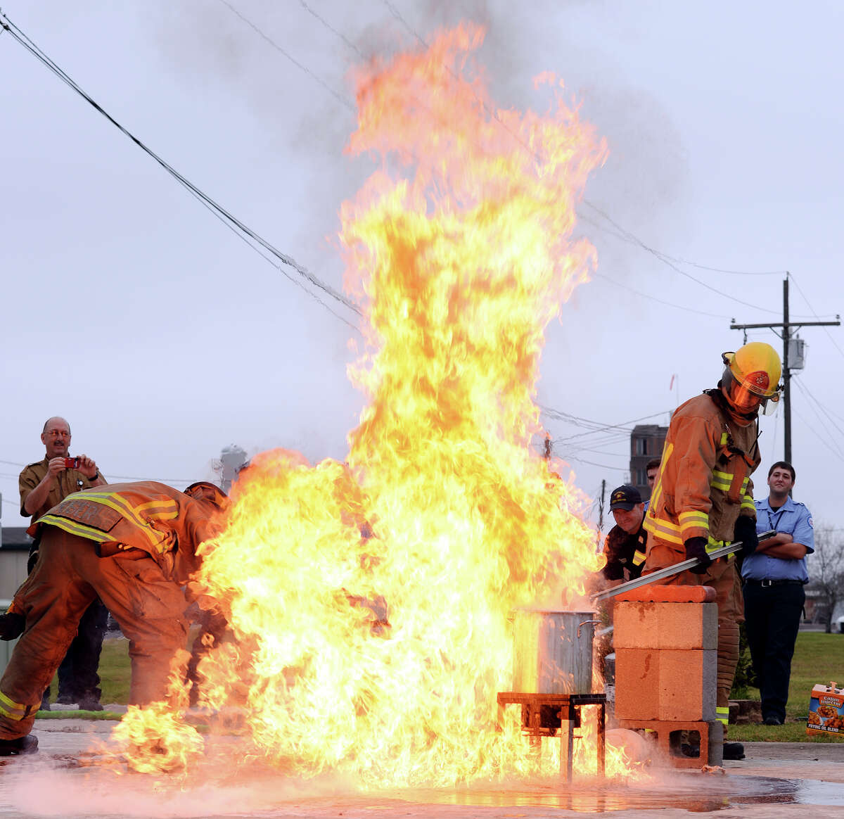 Fireman Matt Kiser, left, steps in to turn off the propane tank while Andy Brown drops a frozen turkey into an overfilled pot of oil as it spills over and catches fire Friday morning. The Beaumont Fire Department demonstrated the dangers of improperly frying a turkey at their training facility Friday morning. Texas is ranked number one in the nation for turkey frying incidents. Photo taken Jake Daniels/@JakeD_in_SETX
