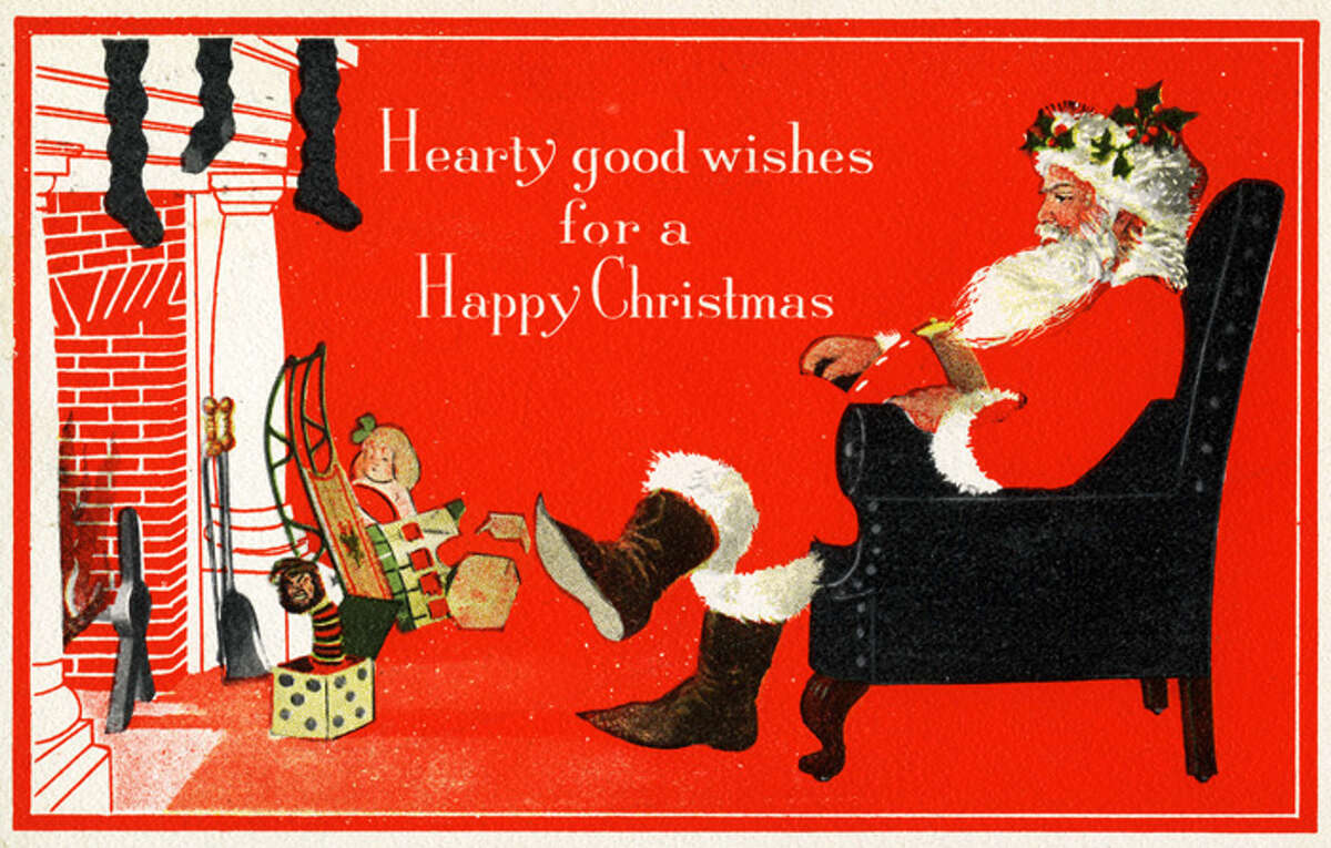 Circa 1910: Greeting card features an illustration of Father Christmas (or Santa Claus) as he sits cross-legged in an armchair before a fireplace, accompanied by the text 'Hearty Good Wishes for a Happy Christmas,' 1910. (Photo by Transcendental Graphics/Getty Images)